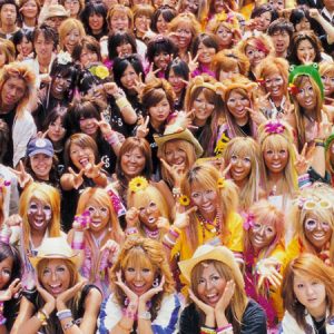 Image of a group photo of ganguro girls and boys. Most of them have dyed blonde hair and intense make-up with white eyeshadow.
