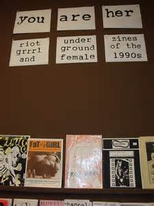 A dsiplay of several Riot Grrrl Zines from the 1990's. The title of the display reads "You are her" a play on words of "you are here"