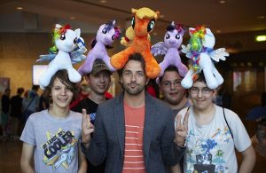 Image depicts five young men with My Little Pony plush ponies on their heads. Picture was taken at the Bronie event BUCK 2013 in Manchester.