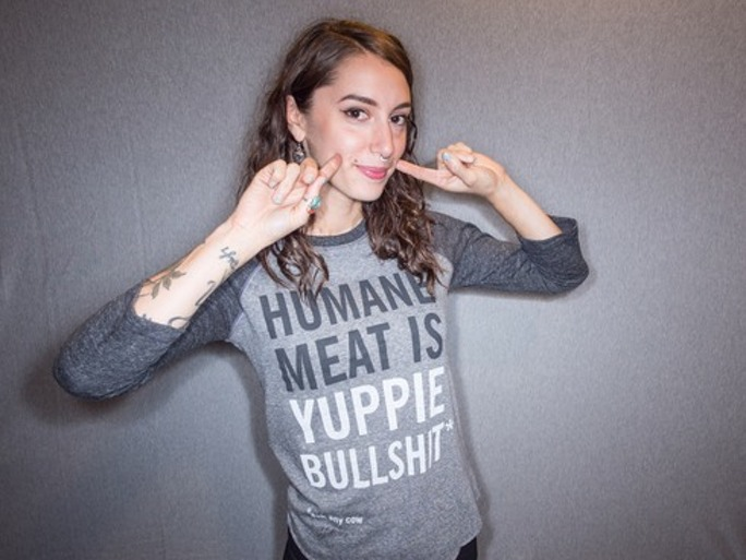 A girl smiling and posing for the camera while wearing a shirt which reads "Human meat is yuppie bullshit"