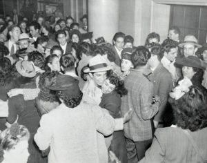 Black and white picture of a crowded room of rioters celebrating after being acquitted.