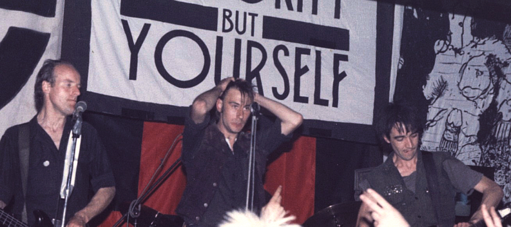 Punk group Crass performs under the banner "There is no authority but yourself"