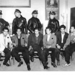 This image shows six pachucos being held in custody by police officers. It is in a black and white color scheme.
