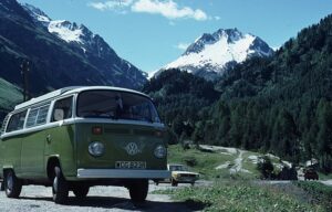 A green Volkswagen van is parked in front of mountains