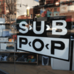 looking through a front window into an Urban Outfitters storefront, with a SubPop Records sign up-front