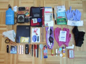 A variety of small useful items, including things like a water bottle cash, an inhaler, a pocketknife, hand sanitizer, cash, masks, and gloves.