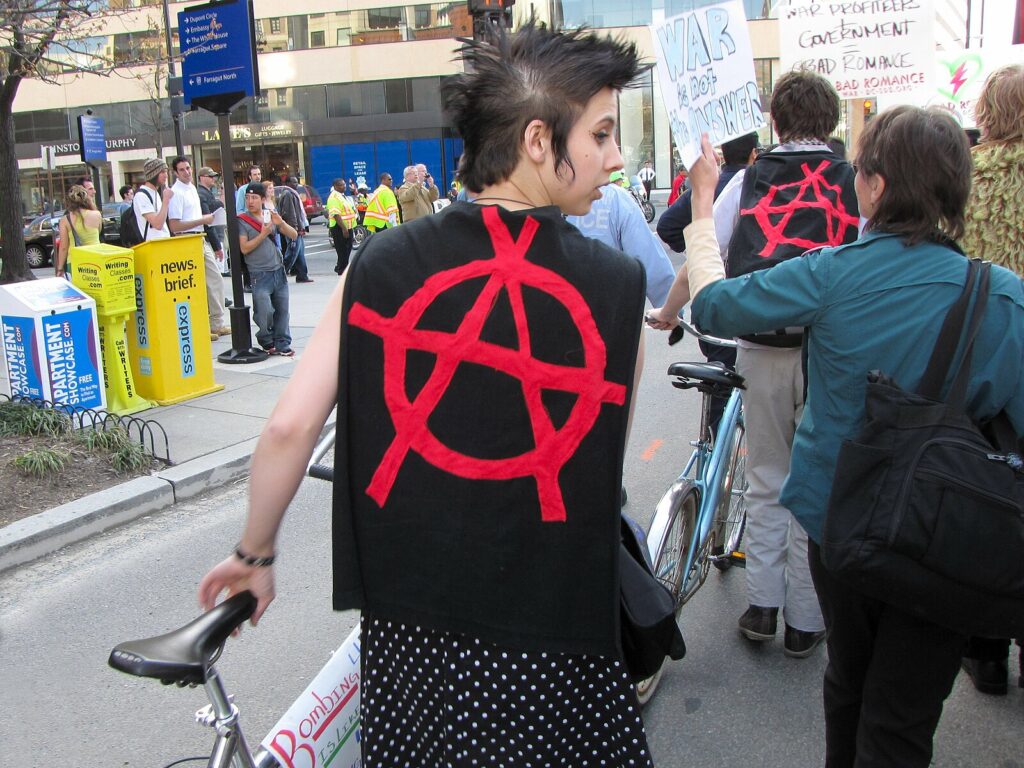 A picture of a punk wearing a vest with an anarchist symbol at an anti-war demonstration.