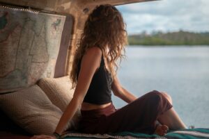 A woman sits in her van gazing out at a body of water